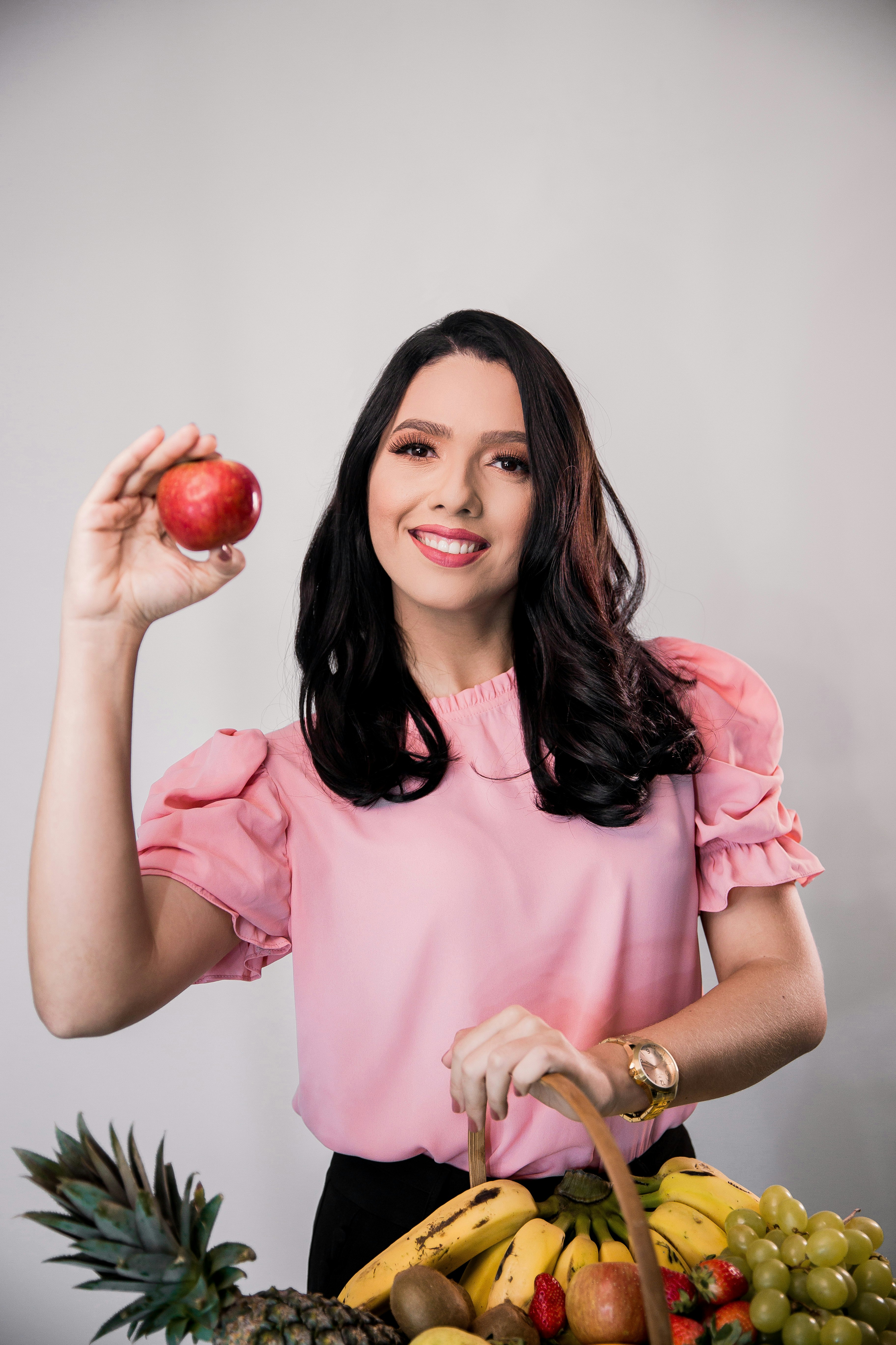 woman in pink crew neck t-shirt holding red apple